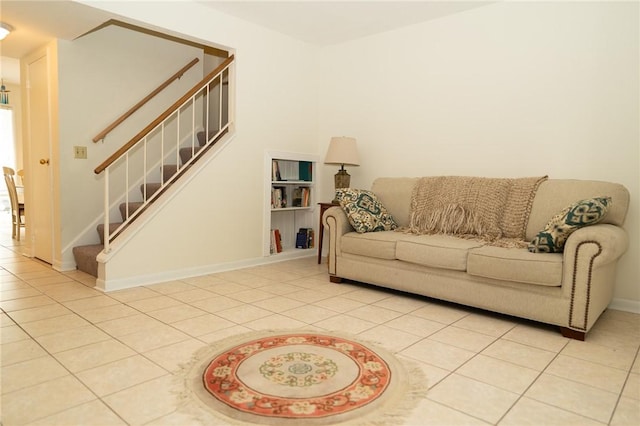 living room featuring stairs, light tile patterned floors, and baseboards