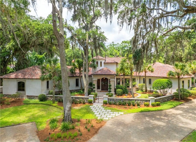 mediterranean / spanish home featuring stucco siding, a front yard, and a tile roof