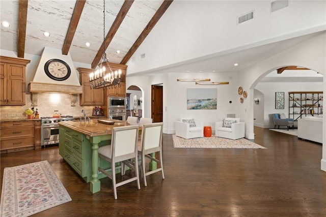 kitchen with arched walkways, stainless steel appliances, custom range hood, high vaulted ceiling, and open floor plan