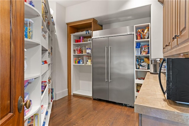 kitchen with stainless steel built in fridge, open shelves, and black microwave