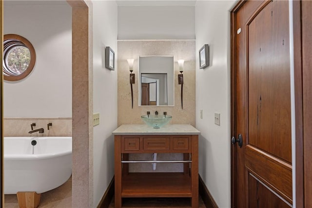 bathroom with vanity, a soaking tub, and baseboards