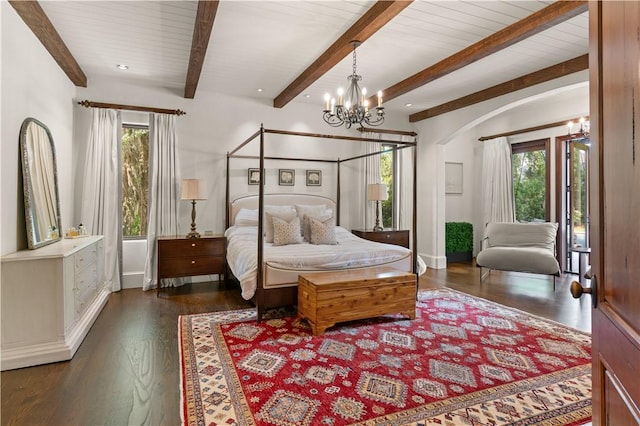 bedroom with beam ceiling, wood finished floors, a chandelier, and multiple windows