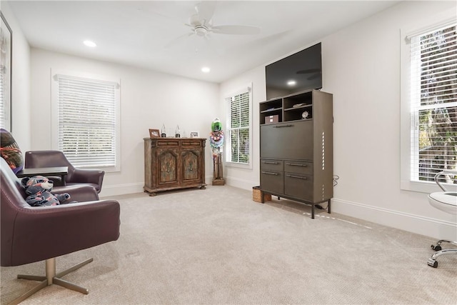 sitting room featuring light carpet, plenty of natural light, and ceiling fan