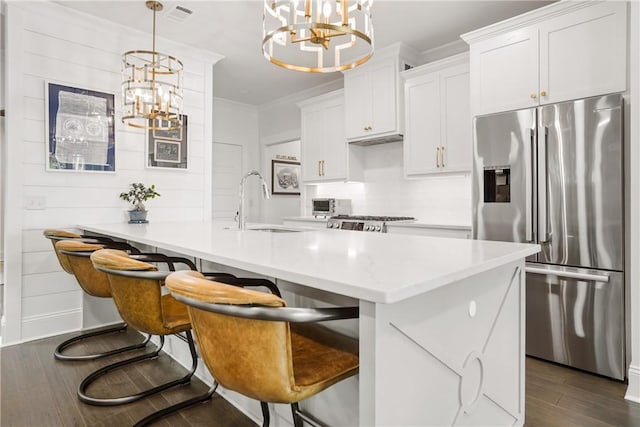 kitchen with pendant lighting, sink, stainless steel fridge, and white cabinets