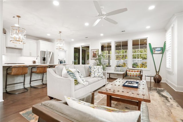 living room with dark hardwood / wood-style floors and ceiling fan with notable chandelier