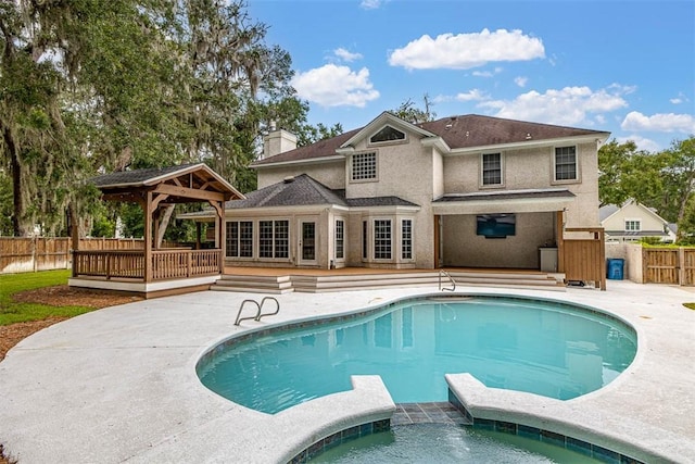 back of house with a gazebo and a pool with hot tub