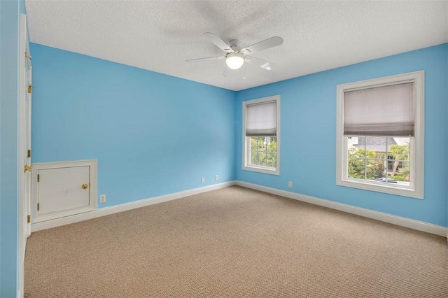 carpeted empty room with ceiling fan and a textured ceiling