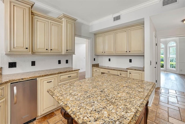 kitchen with cream cabinetry, stainless steel refrigerator, and light stone counters