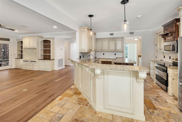 kitchen featuring light stone counters, decorative light fixtures, cream cabinetry, a kitchen bar, and appliances with stainless steel finishes