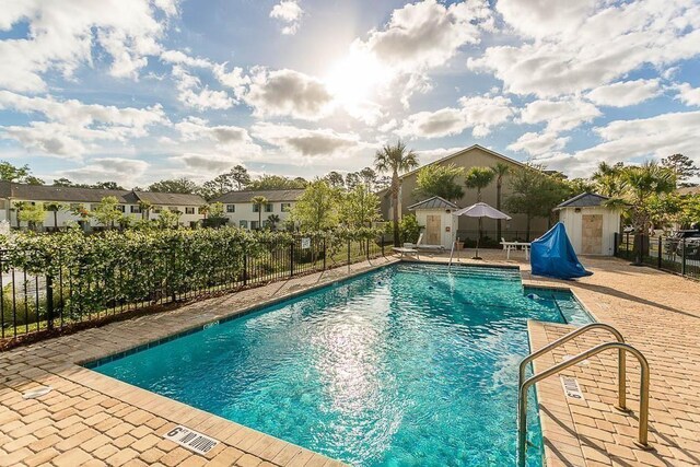 view of swimming pool featuring a storage unit and a patio