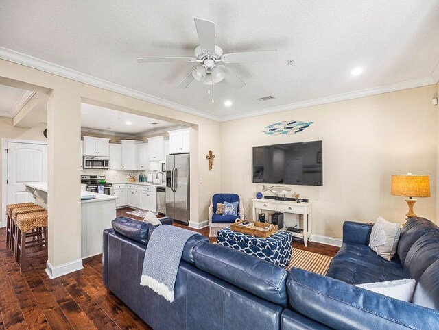 living room with crown molding, ceiling fan, dark wood-type flooring, and sink