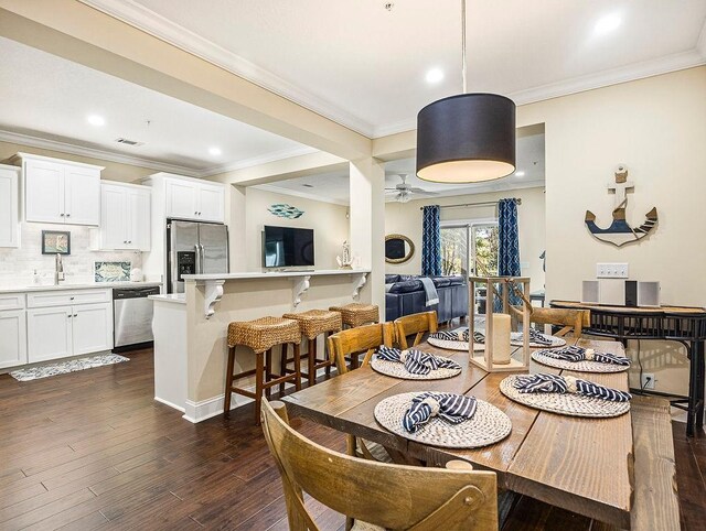 dining space featuring ceiling fan, crown molding, sink, and dark wood-type flooring