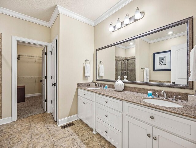 bathroom with vanity, a shower with door, a textured ceiling, and ornamental molding