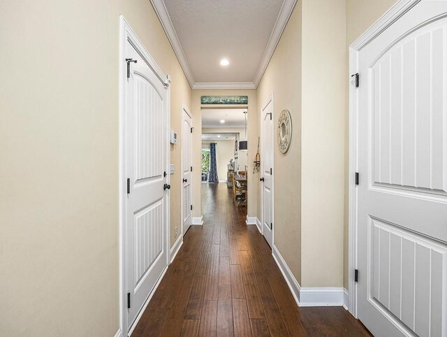 hallway with dark wood-type flooring and ornamental molding