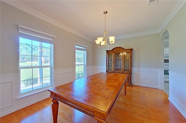 6121 Stoney Brook Dr, Blackshear, GA 31516 - dining space featuring arched walkways, a notable chandelier, light wood-type flooring, and a wainscoted wall