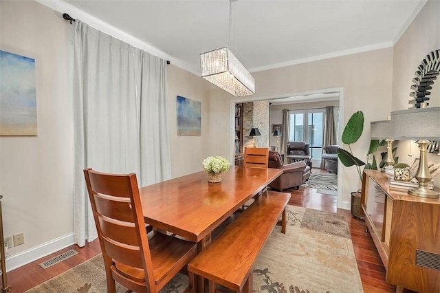 407 Butler Ave, Saint Simons Island, GA 31522 - dining area featuring dark wood-style flooring, a chandelier, ornamental molding, and baseboards