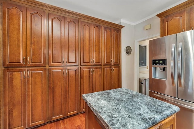 407 Butler Ave, Saint Simons Island, GA 31522 - kitchen featuring stainless steel fridge with ice dispenser, a kitchen island, brown cabinetry, light wood finished floors, and dark stone counters