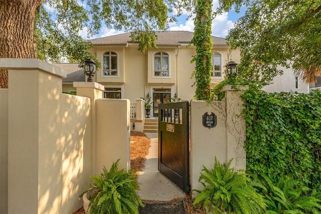 407 Butler Ave, Saint Simons Island, GA 31522 - view of front of house featuring stucco siding, a gate, and roof with shingles