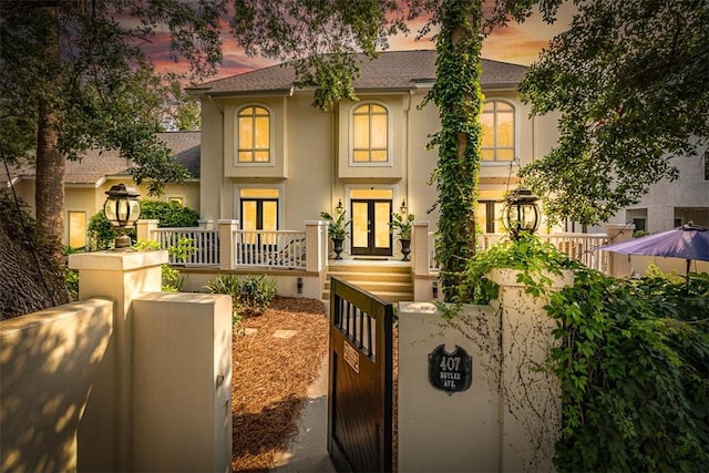 407 Butler Ave, Saint Simons Island, GA 31522 - view of front facade featuring french doors, stucco siding, roof with shingles, a gate, and a fenced front yard