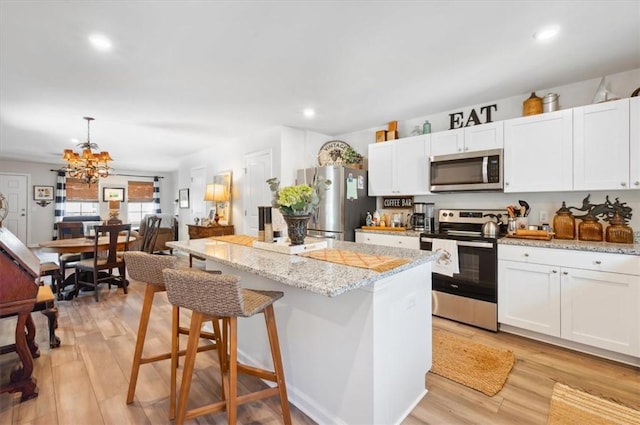 102 Cathead Ln, Darien, GA 31305 - kitchen with light wood finished floors, white cabinetry, a chandelier, a kitchen island, and appliances with stainless steel finishes