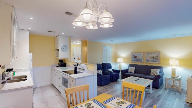 dining area featuring a chandelier, ornamental molding, sink, and light hardwood / wood-style flooring