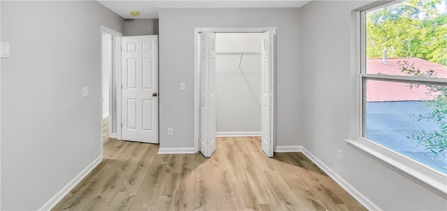 unfurnished bedroom featuring multiple windows, light hardwood / wood-style flooring, and a closet