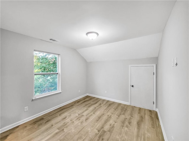 additional living space with vaulted ceiling and light wood-type flooring