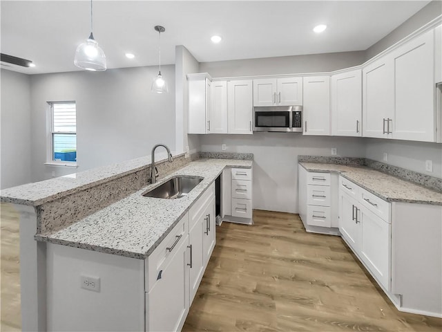 kitchen with sink, hanging light fixtures, kitchen peninsula, and white cabinets