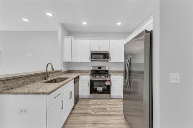 1329 New Castle St, Savannah, GA 31415 - kitchen featuring appliances with stainless steel finishes, a sink, light stone counters, white cabinetry, and light wood-type flooring