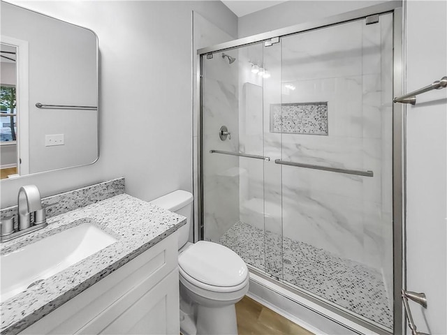 bathroom with vanity, toilet, and a shower with door