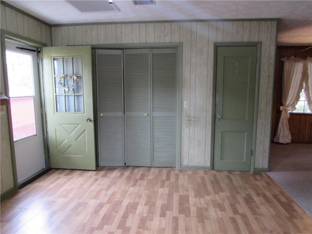 unfurnished bedroom featuring wood walls and light colored carpet