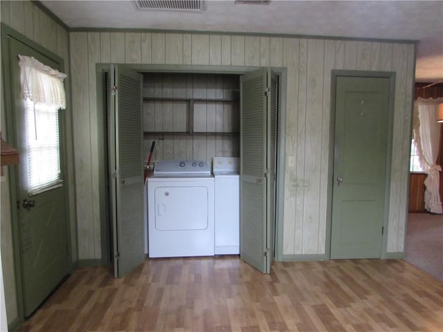 laundry room with plenty of natural light, wooden walls, and washing machine and clothes dryer