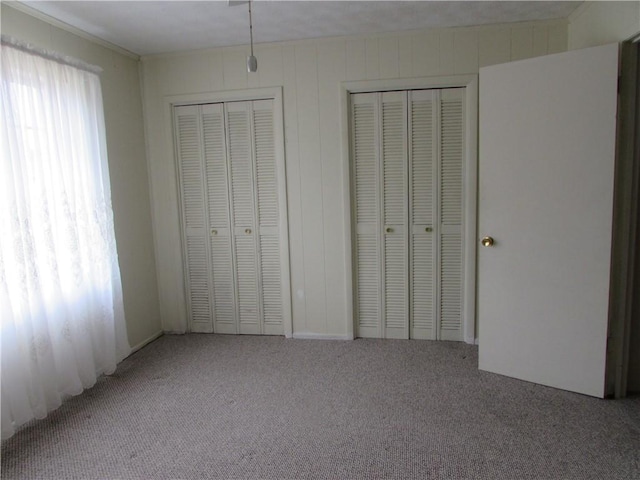 unfurnished bedroom featuring carpet floors and multiple closets