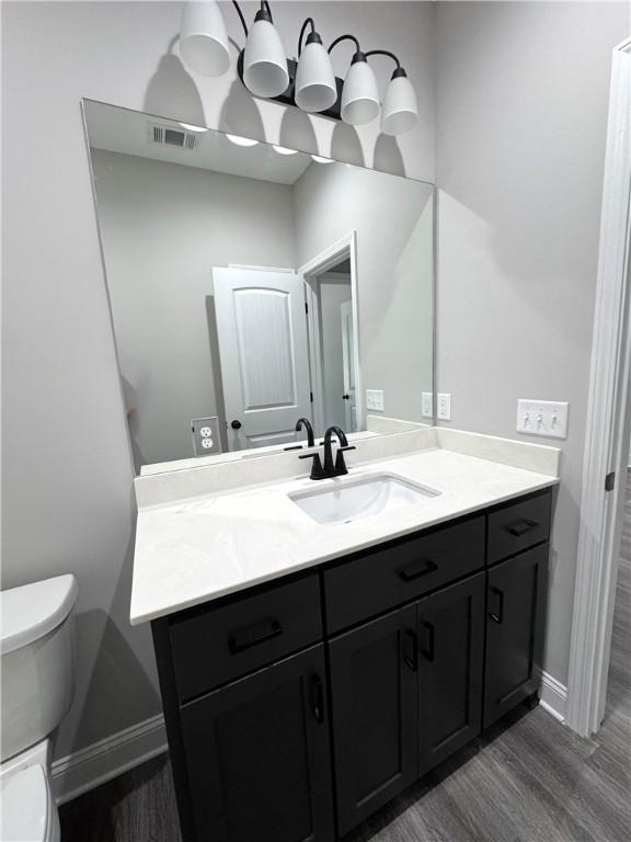 1029 N Church St, Odum, GA 31555 - bathroom with toilet, vanity, wood finished floors, and baseboards