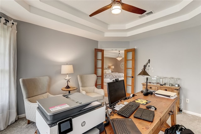 carpeted office space featuring french doors, ceiling fan, and a raised ceiling