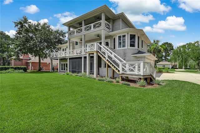 rear view of property with ceiling fan, a yard, a balcony, and a sunroom