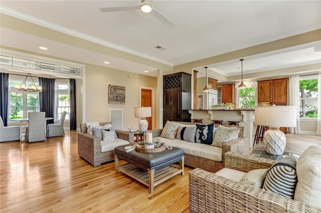 living room with ornamental molding, ceiling fan with notable chandelier, and light hardwood / wood-style flooring