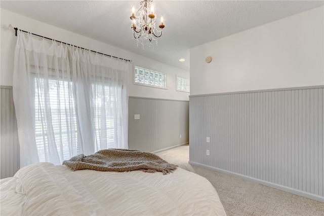 carpeted bedroom with an inviting chandelier and a textured ceiling