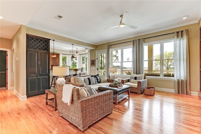 living room with crown molding, light hardwood / wood-style floors, and ceiling fan