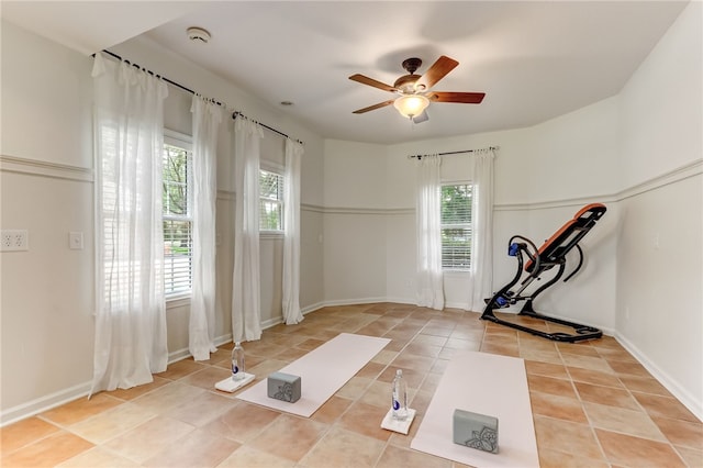 exercise room with light tile patterned floors and ceiling fan