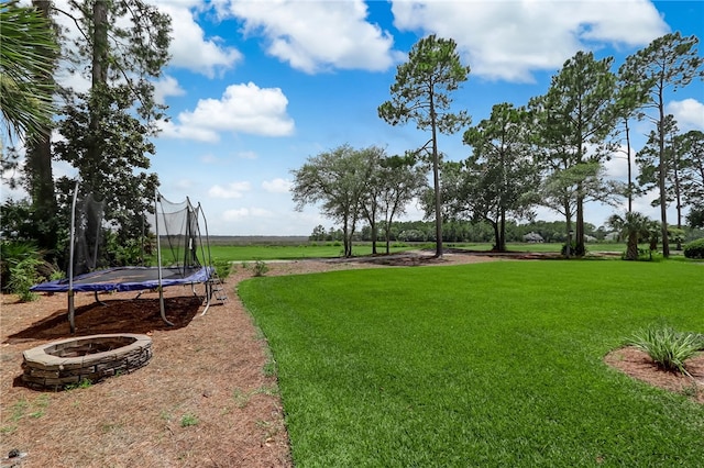 view of yard with a trampoline and a fire pit