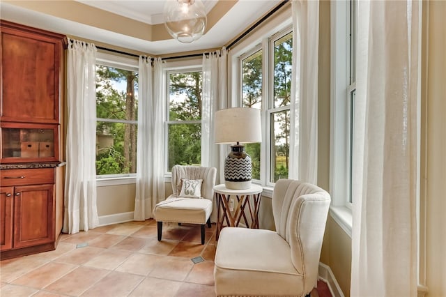 living area with plenty of natural light, ornamental molding, a raised ceiling, and light tile patterned flooring