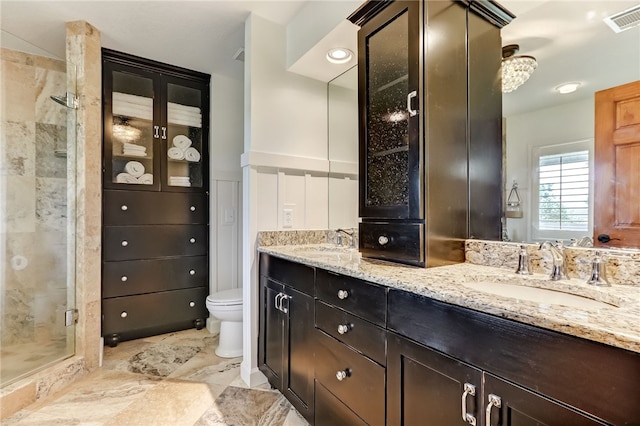 bathroom featuring vanity, a shower with door, and toilet