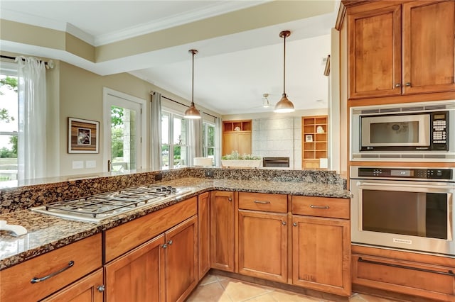 kitchen featuring hanging light fixtures, dark stone counters, a healthy amount of sunlight, and appliances with stainless steel finishes