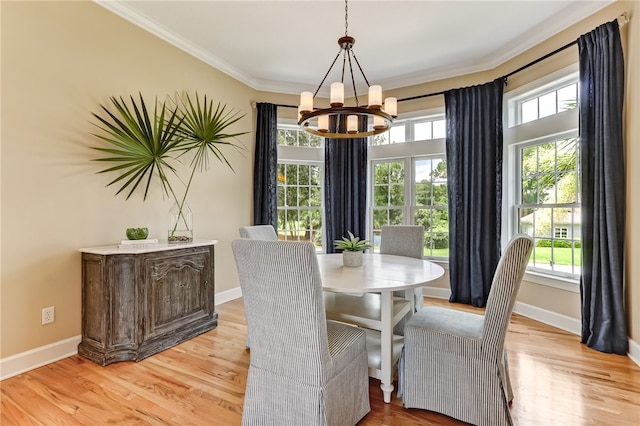 dining space with ornamental molding, a chandelier, and light hardwood / wood-style floors