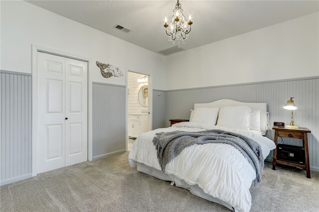 bedroom featuring an inviting chandelier, connected bathroom, carpet floors, and a closet