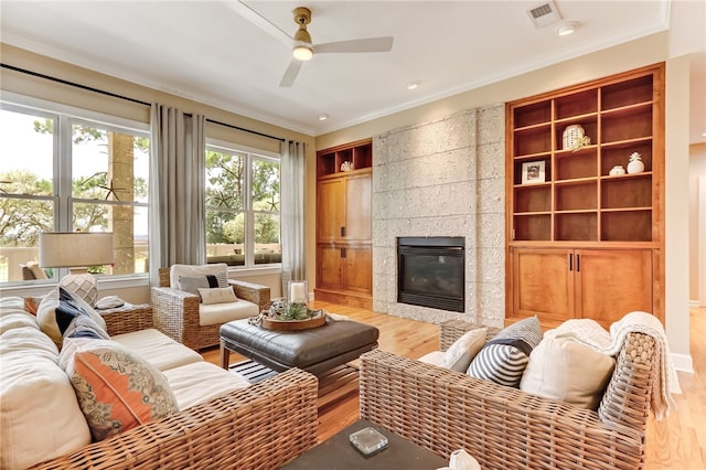 living room featuring hardwood / wood-style flooring, a fireplace, ornamental molding, and ceiling fan