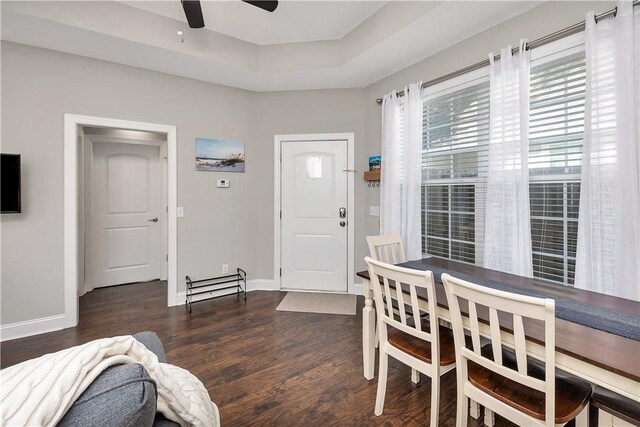 dining space featuring a raised ceiling, ceiling fan, and dark hardwood / wood-style flooring