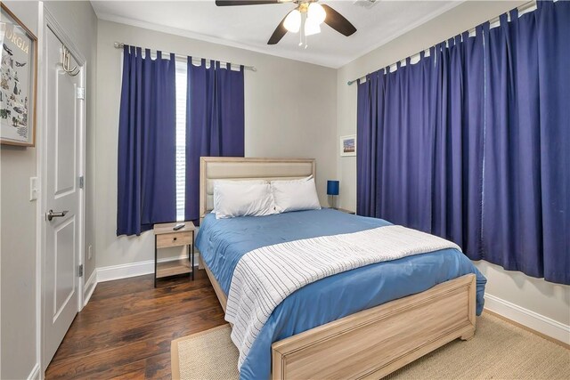 bedroom with ceiling fan, crown molding, and dark wood-type flooring