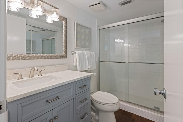 bathroom with wood-type flooring, vanity, toilet, and a shower with door